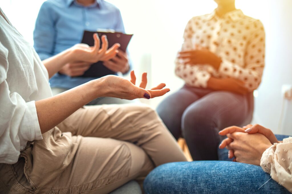 An image of multiple people sitting in conversation at group therapy