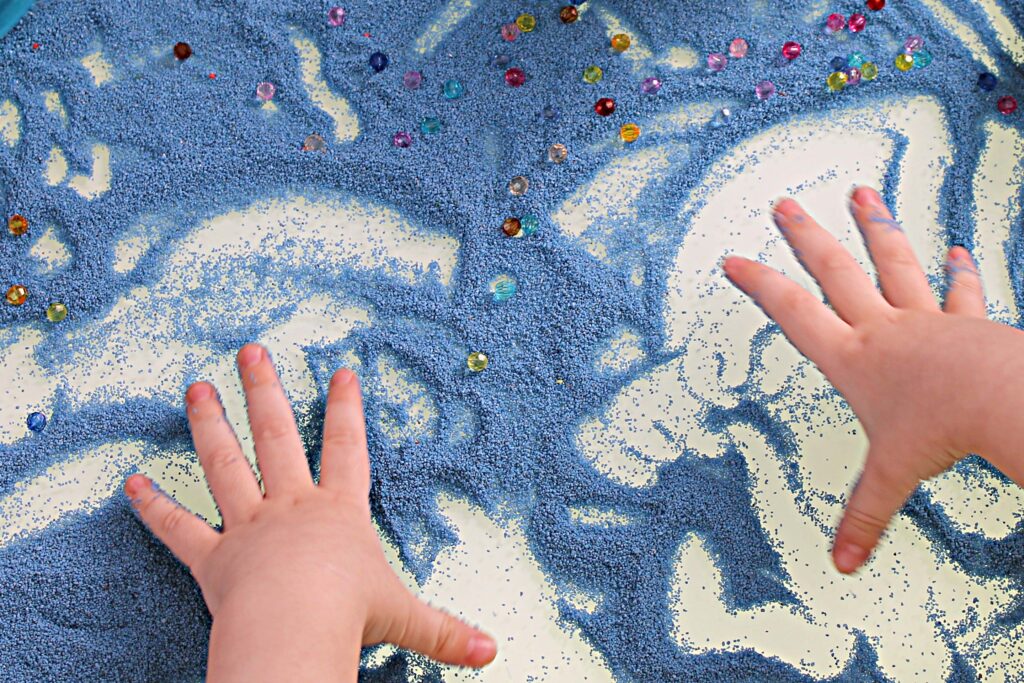 A child plays with sensory beads and sand during a therapy session